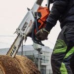 A worker using a chainsaw to cut a tree trunk, showcasing essential tools for tree removal in winter conditions.