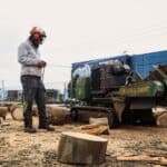 Worker preparing small tree stump grinding with heavy-duty stump grinder