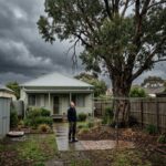 Melbourne homeowner inspecting a backyard tree for dead branches and storm risk before high winds.
